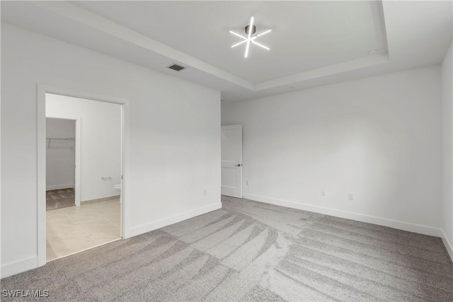 spare room featuring light carpet and a raised ceiling