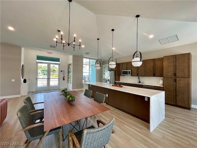 kitchen with appliances with stainless steel finishes, a center island with sink, pendant lighting, and sink