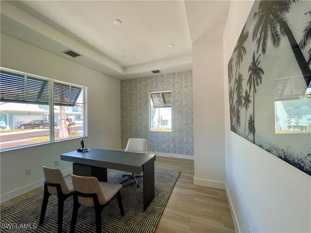 office with a tray ceiling and light hardwood / wood-style flooring