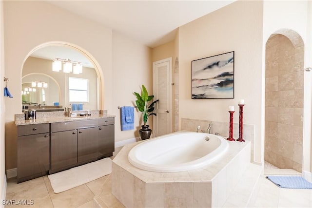 bathroom with tile patterned flooring, vanity, and a relaxing tiled tub