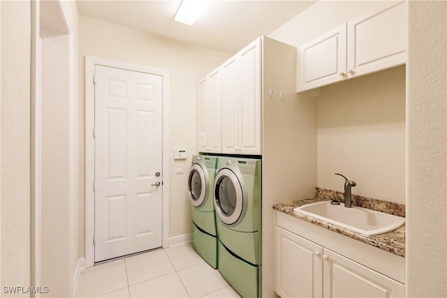 clothes washing area with washer and dryer, light tile patterned floors, cabinets, and sink