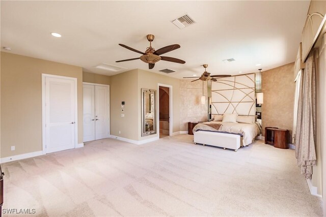 unfurnished bedroom with ceiling fan, light colored carpet, and multiple closets