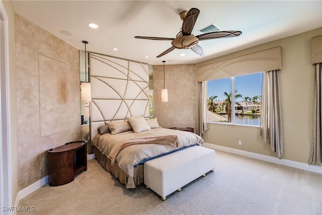 bedroom featuring ceiling fan, a water view, and light carpet