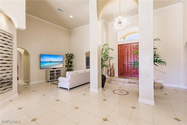 tiled entrance foyer featuring a towering ceiling, crown molding, and a notable chandelier