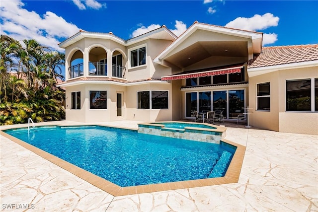 rear view of house with a pool with hot tub, a patio area, and a balcony