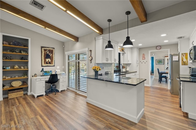 kitchen with appliances with stainless steel finishes, pendant lighting, white cabinets, and kitchen peninsula