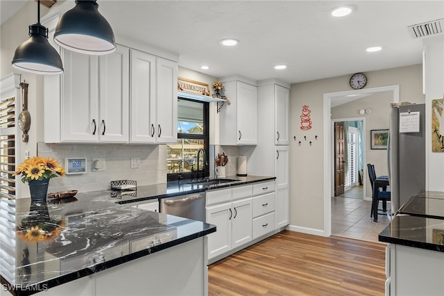 kitchen with decorative light fixtures, backsplash, sink, appliances with stainless steel finishes, and white cabinets