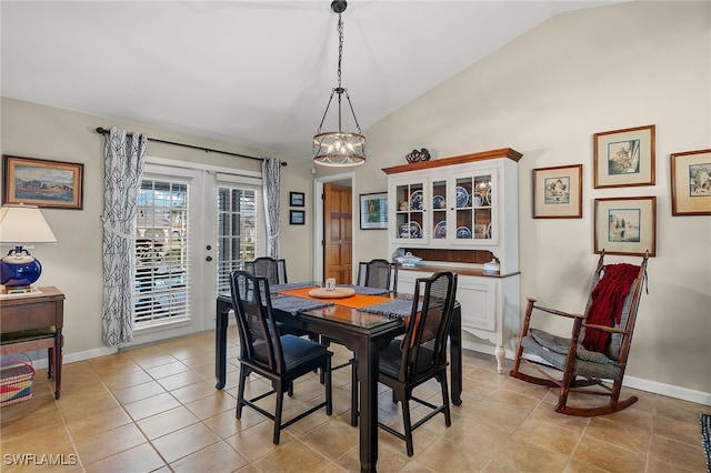 tiled dining room with lofted ceiling, french doors, and a chandelier