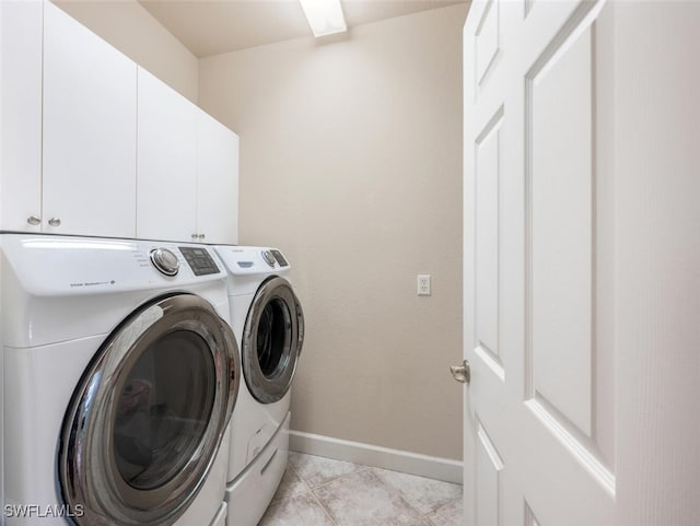 laundry room featuring light tile patterned floors, washing machine and clothes dryer, and cabinets