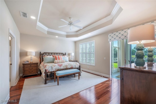 bedroom with ceiling fan, dark hardwood / wood-style floors, access to outside, crown molding, and a tray ceiling