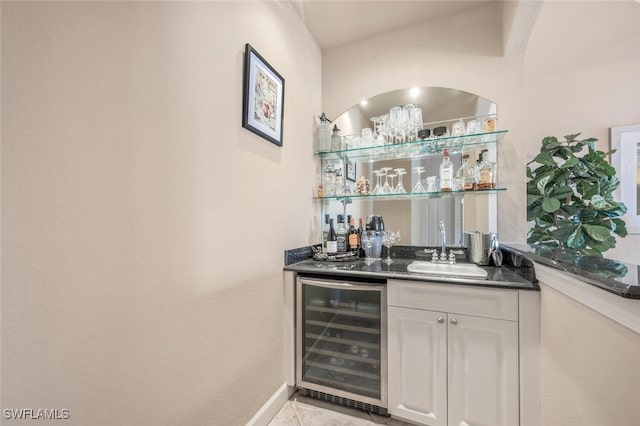 bar with light tile patterned floors, sink, white cabinets, and wine cooler