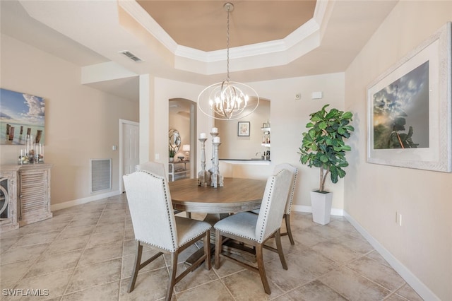 tiled dining space featuring a tray ceiling, ornamental molding, and a notable chandelier