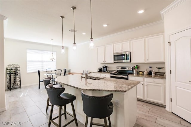 kitchen featuring sink, stainless steel appliances, an island with sink, pendant lighting, and white cabinets