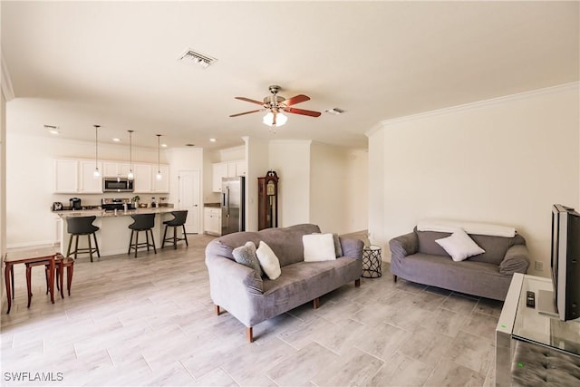 living room with ceiling fan and crown molding