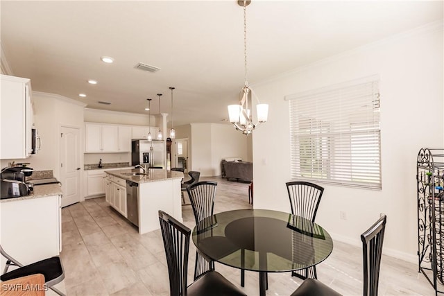 dining room featuring light hardwood / wood-style floors, ornamental molding, sink, and an inviting chandelier