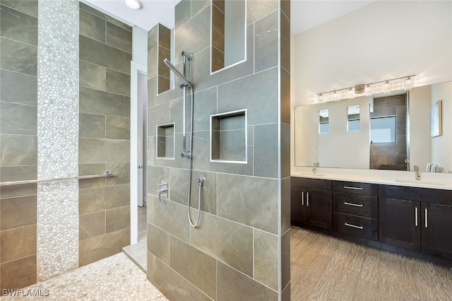 bathroom with tiled shower, vanity, and wood-type flooring