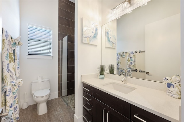 bathroom with vanity, hardwood / wood-style floors, toilet, and tiled shower