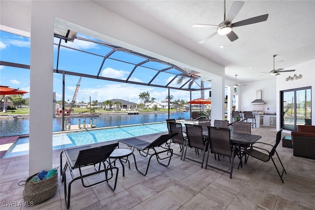 view of patio featuring area for grilling, a lanai, ceiling fan, and a water view