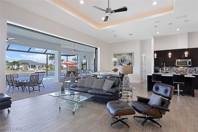 living room featuring a raised ceiling and ceiling fan