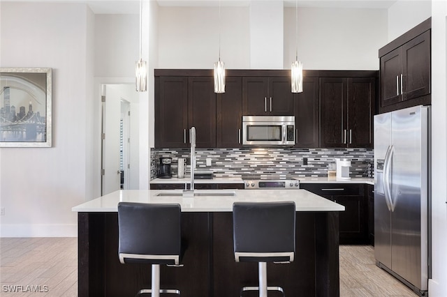 kitchen featuring appliances with stainless steel finishes, sink, pendant lighting, and a kitchen breakfast bar