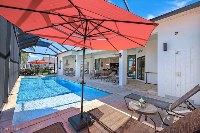 view of swimming pool featuring ceiling fan, a patio, outdoor lounge area, and glass enclosure