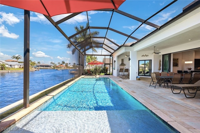 view of pool with a lanai, ceiling fan, a water view, a patio area, and a bar