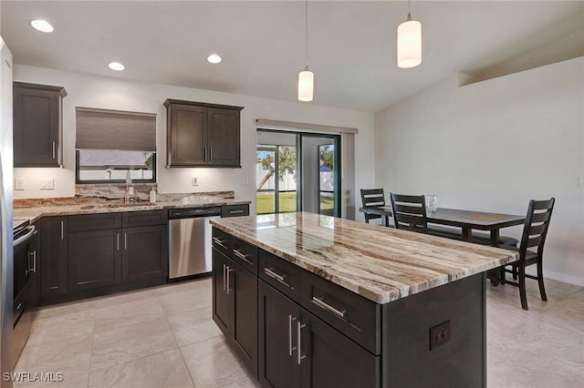 kitchen featuring a center island, sink, hanging light fixtures, stainless steel appliances, and light stone counters