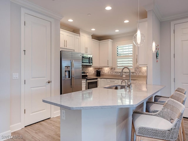 kitchen with kitchen peninsula, appliances with stainless steel finishes, a kitchen bar, white cabinets, and hanging light fixtures