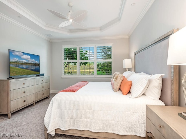 bedroom with ceiling fan, light colored carpet, ornamental molding, and a tray ceiling