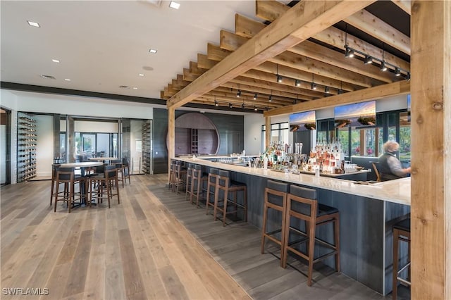 kitchen featuring kitchen peninsula, a breakfast bar, track lighting, and hardwood / wood-style flooring