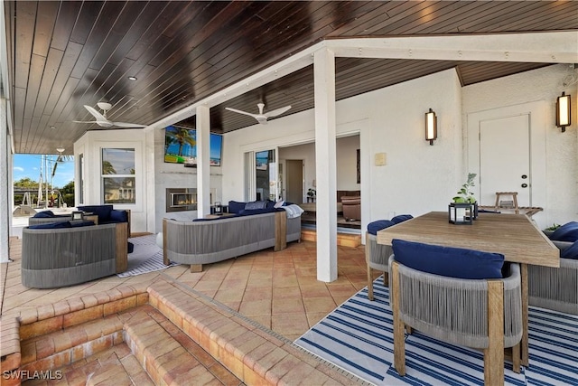 view of patio featuring ceiling fan and an outdoor living space with a fireplace