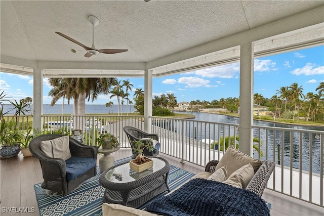 sunroom featuring a water view, ceiling fan, and plenty of natural light