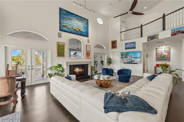 living room featuring ceiling fan, a towering ceiling, dark hardwood / wood-style floors, and french doors