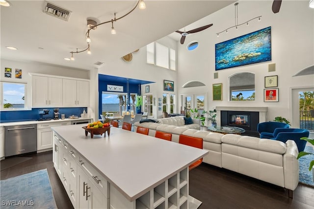 kitchen with dark hardwood / wood-style flooring, stainless steel dishwasher, a center island, and white cabinets