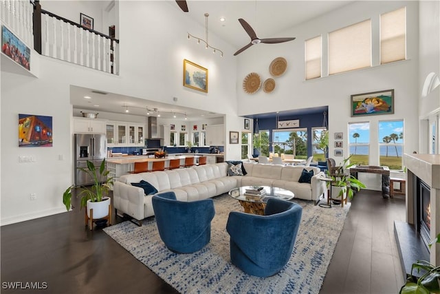 living room with a towering ceiling, dark wood-type flooring, and a multi sided fireplace