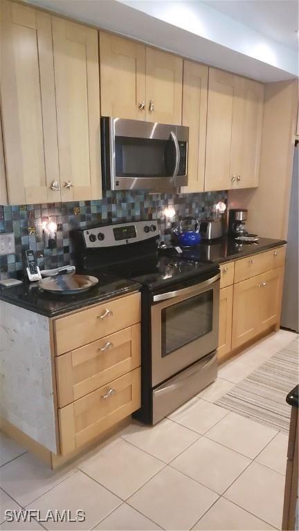 kitchen with appliances with stainless steel finishes, tasteful backsplash, light tile patterned floors, and light brown cabinetry