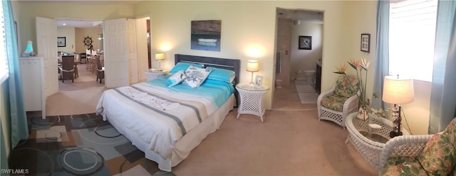 bedroom with ensuite bath and light carpet