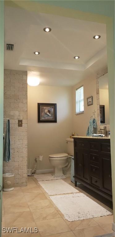 bathroom featuring vanity, a tray ceiling, and toilet