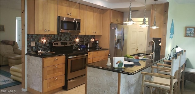 kitchen with decorative backsplash, appliances with stainless steel finishes, a kitchen breakfast bar, light tile patterned floors, and decorative light fixtures