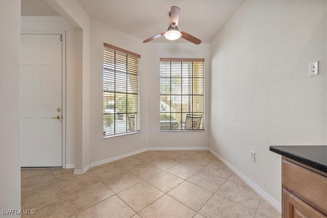 unfurnished dining area with light tile patterned floors and ceiling fan