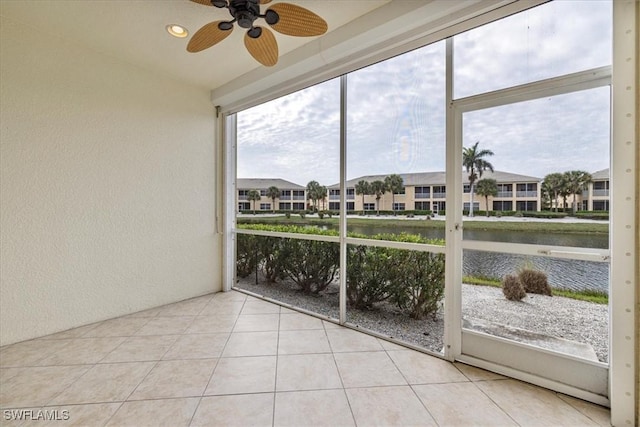 unfurnished sunroom with ceiling fan and a water view