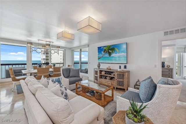 living room featuring a healthy amount of sunlight, a water view, light tile patterned flooring, and an inviting chandelier