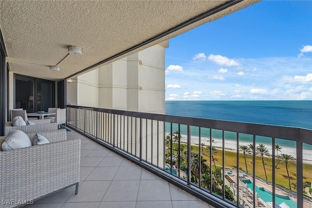 balcony with a water view, a beach view, and a ceiling fan