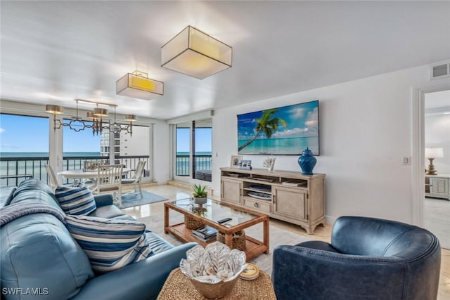 living area with a water view, an inviting chandelier, baseboards, and visible vents