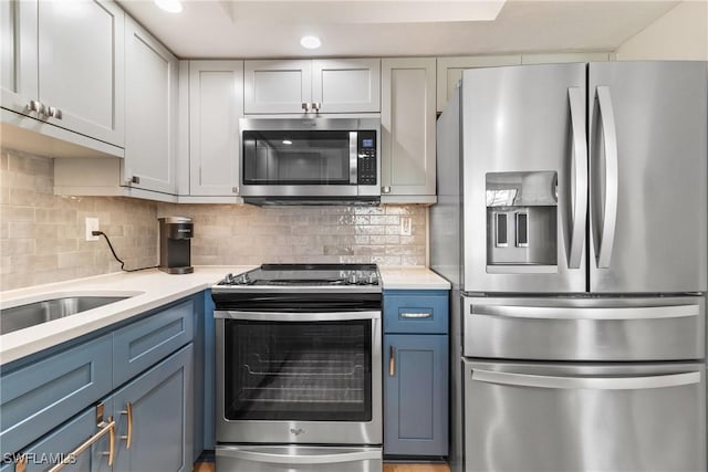 kitchen with blue cabinetry, tasteful backsplash, and appliances with stainless steel finishes