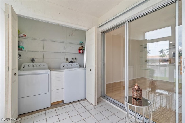 clothes washing area with washer and dryer and light tile patterned floors