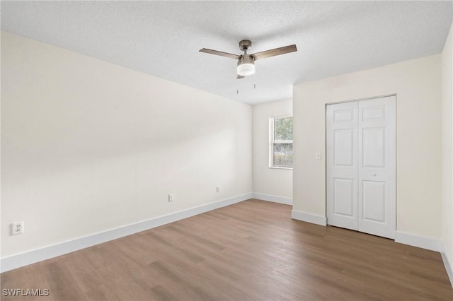 unfurnished bedroom with hardwood / wood-style flooring, ceiling fan, a textured ceiling, and a closet