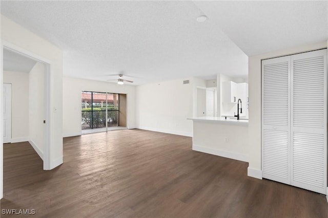 unfurnished living room with sink, ceiling fan, dark hardwood / wood-style flooring, and a textured ceiling