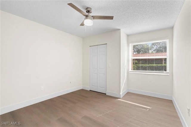 unfurnished bedroom featuring ceiling fan, light hardwood / wood-style floors, a textured ceiling, and a closet