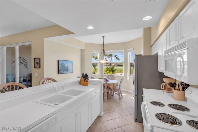 kitchen featuring white appliances, a sink, white cabinets, light countertops, and decorative light fixtures